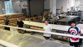 Four undergraduate students who aided production last summer hold up the final “di-counter” that was fabricated, which they all signed. (UVA Experimental High Energy Physics photo)