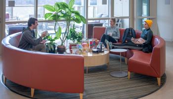 Three Ph.D. students from the Department of Biology are seated in a lounge enjoying a graduate student coffee hour event.