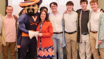 Arts & Sciences Dean Christa Acampora poses with UVA's Cavman mascot and members of the Hullabahoos a capella singing group.