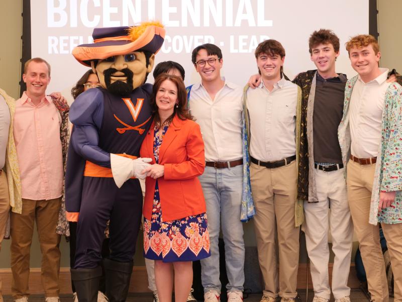 Arts & Sciences Dean Christa Acampora poses with UVA's Cavman mascot and members of the Hullabahoos a capella singing group.