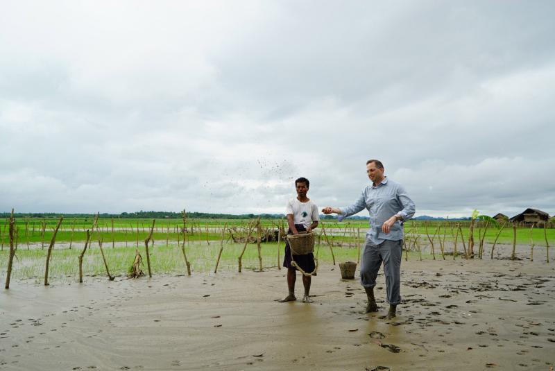 U.S. Ambassador to Burma Derek Mitchell helps a rice farmer, whose crop was destroyed in the July-August floods, to replant rice seeds. Rakhine State, Burma, August 2015.