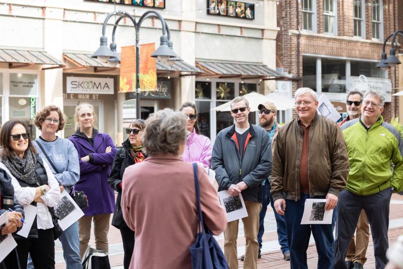 People standing and listening to a tour guide during a historical walking tour of Charlottesville.
